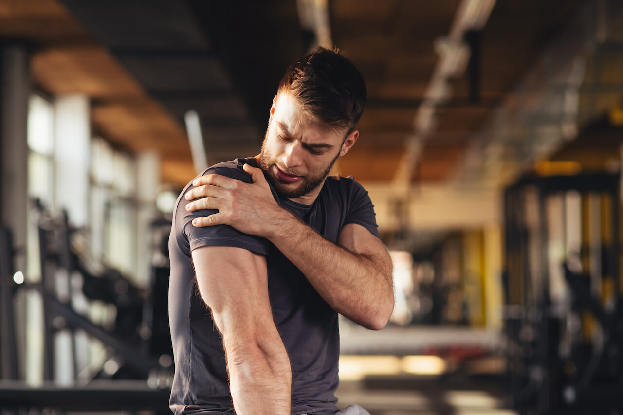 man at gym grabbing shoulder in pain