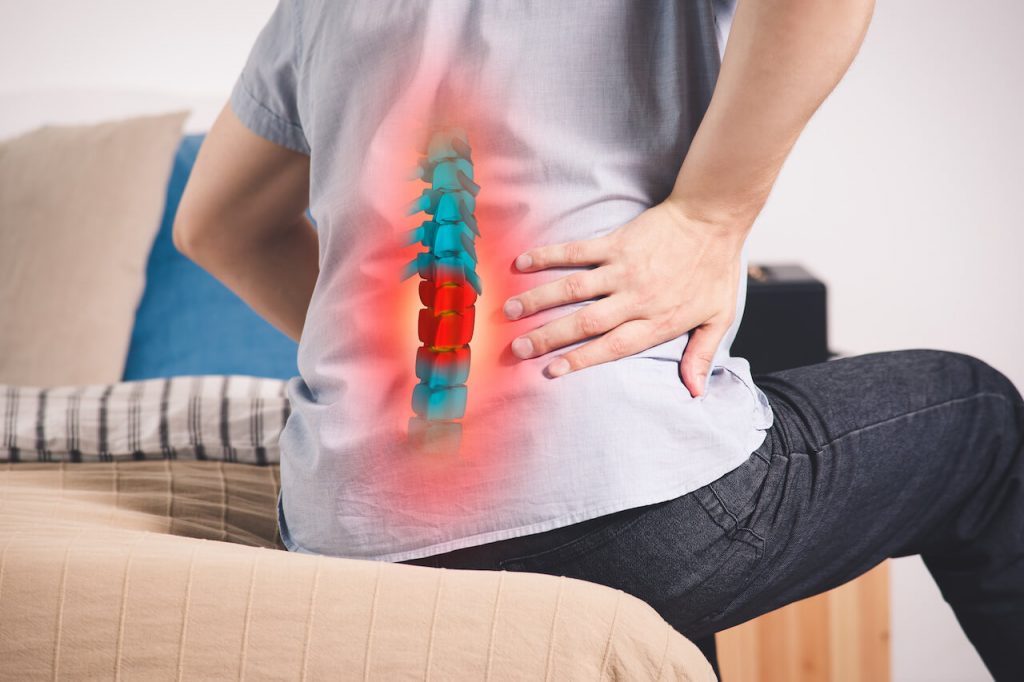 back of man sitting on bed with spine graphic overlay indicating back pain