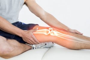 man on floor grabbing leg with graphic overlay of knee joint shown